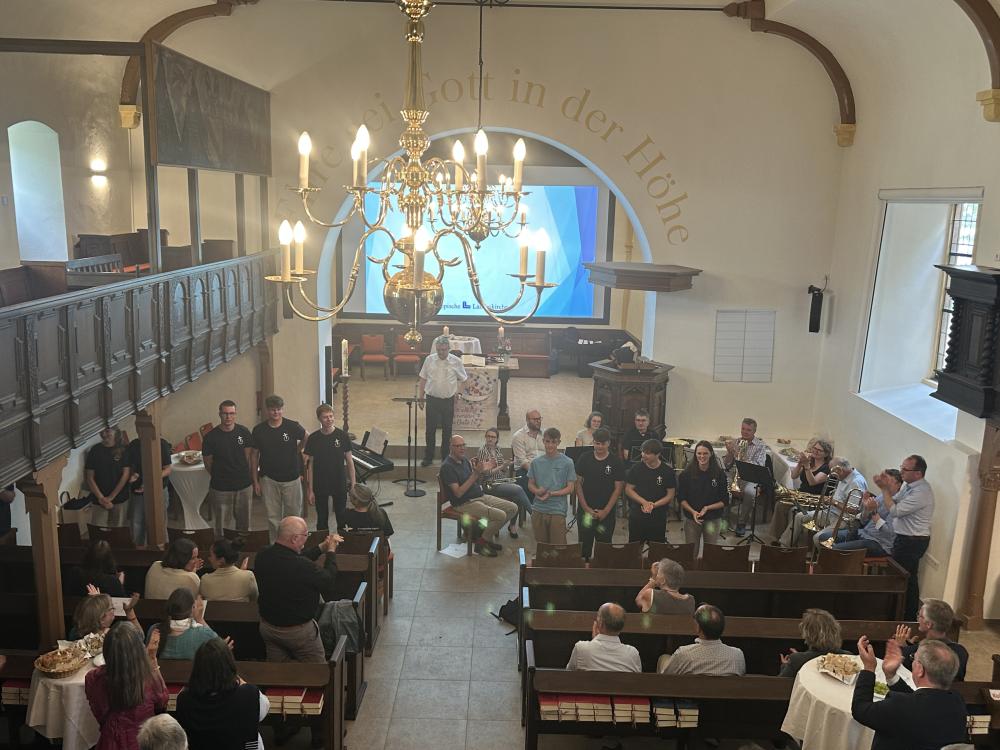 Zukunftssynode eröffnet - Begeisterung: Der Gottesdienst der Jugendlichen erhielt viel Applaus. Jugendliche stehen vorne in der Kirche. Menschen in den Bankreihen stehen und applaudieren.